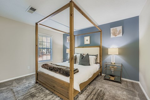 A bedroom with a four poster bed and a rug on the floor.