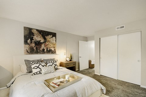 A bedroom with a large bed and a painting on the wall.