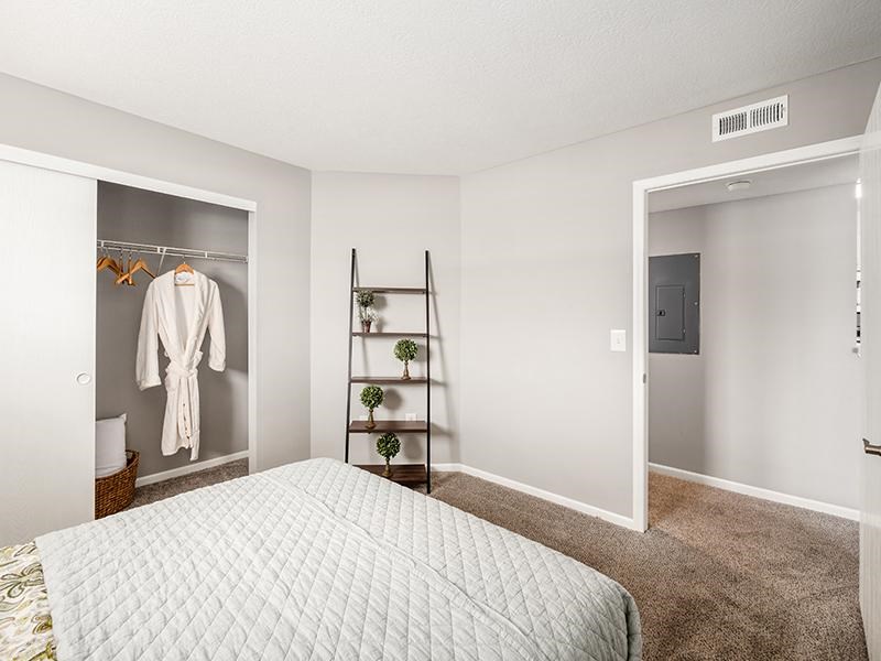 A bedroom with a bed, a closet, and a shelf.