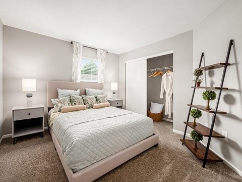 A bedroom with a large bed and a wooden ladder.