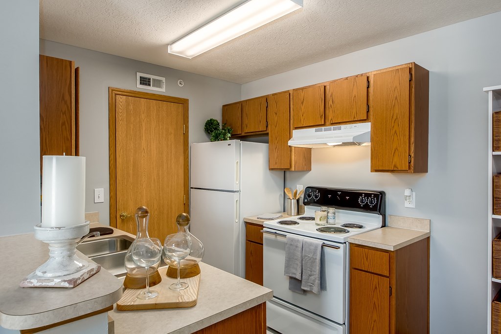 A kitchen with wooden cabinets and a white stove top oven.