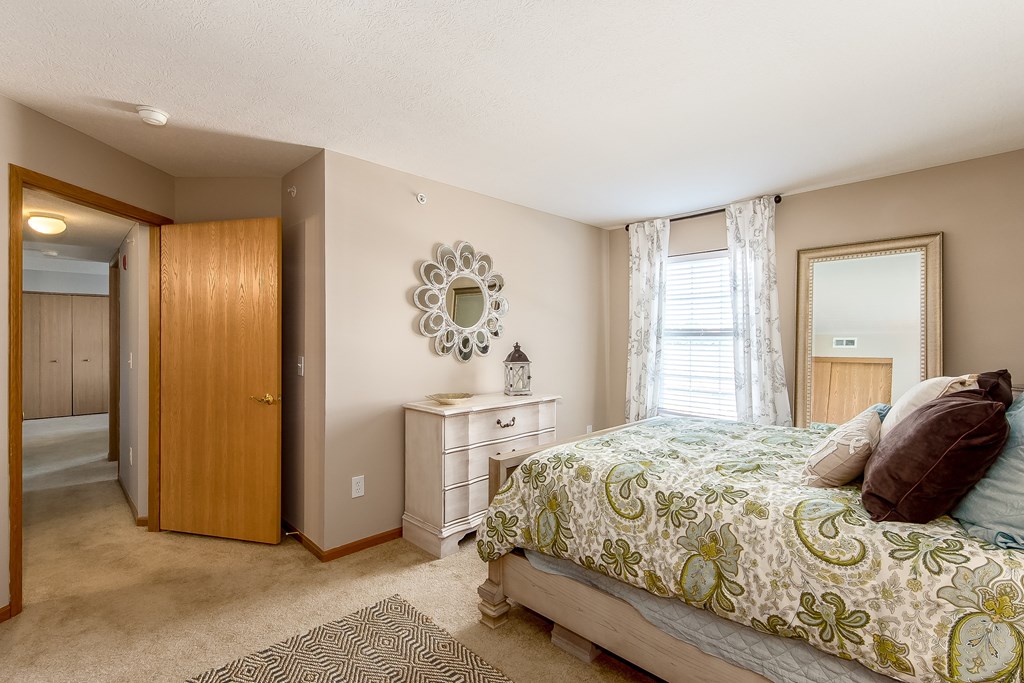 A bedroom with a bed, dresser, and mirror.