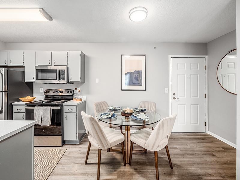 A modern kitchen with a glass dining table set for four.