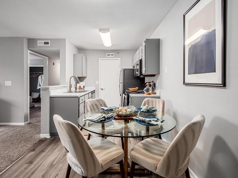 A modern kitchen with a glass dining table and chairs.