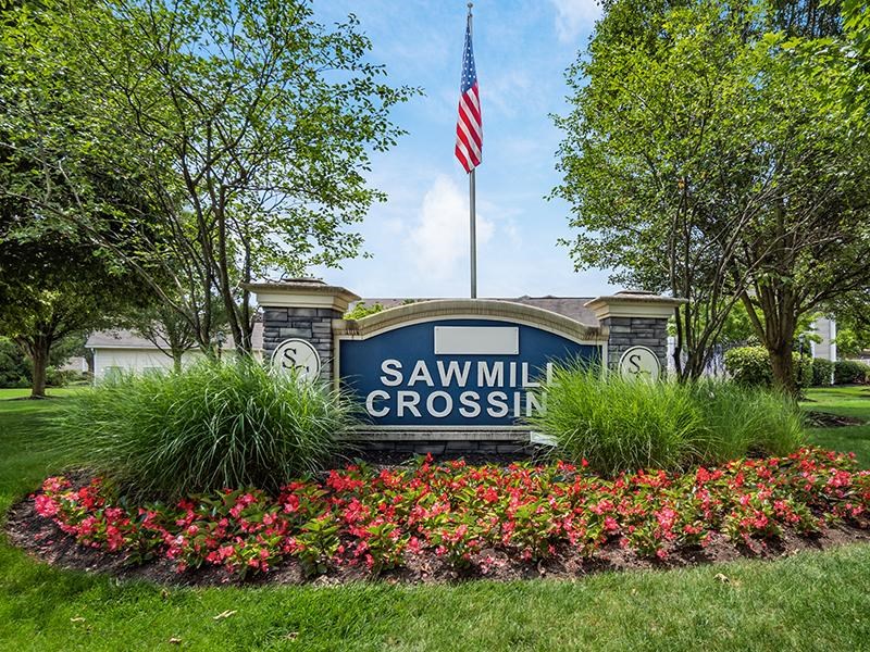 A sign that says Sawmill Crossing is in front of a building.