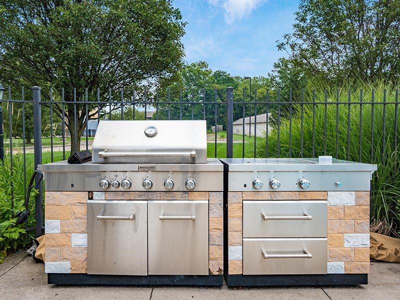 Two stone BBQs with a grill on top and a smaller one on the right.