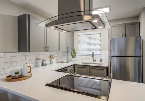 A modern kitchen with a stainless steel refrigerator and a large island with a sink.