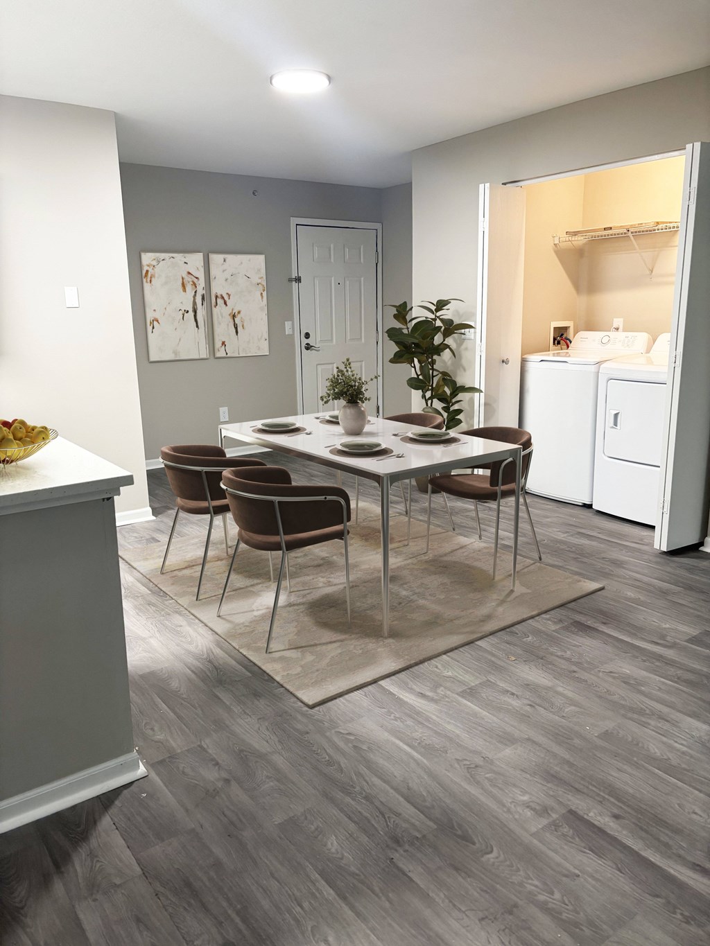 A dining room with a table set for four and chairs around it.