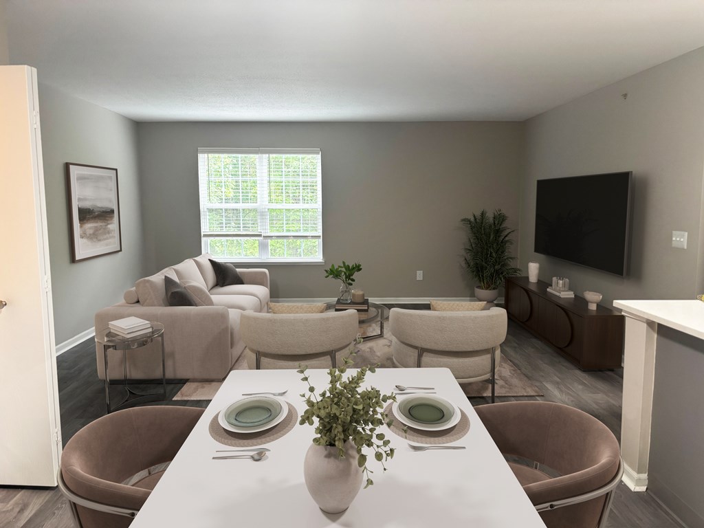 A dining room with a table set for two and a television mounted on the wall.