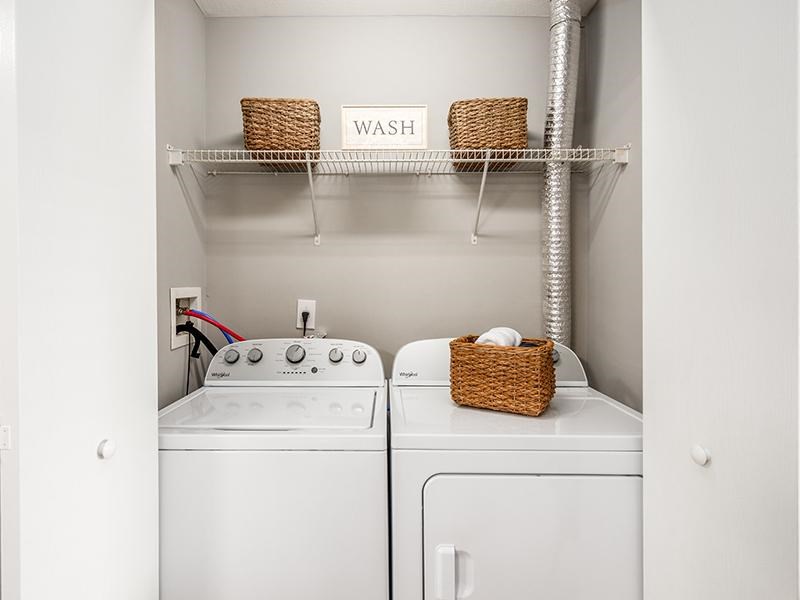 A laundry room with a washer and dryer and a basket on top of the dryer.