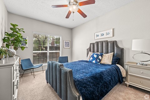 A bedroom with a bed, chair, and ceiling fan.