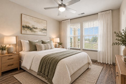 A bedroom with a large bed, a ceiling fan, and a painting on the wall.