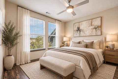 A bedroom with a large bed, a bench, and a ceiling fan.