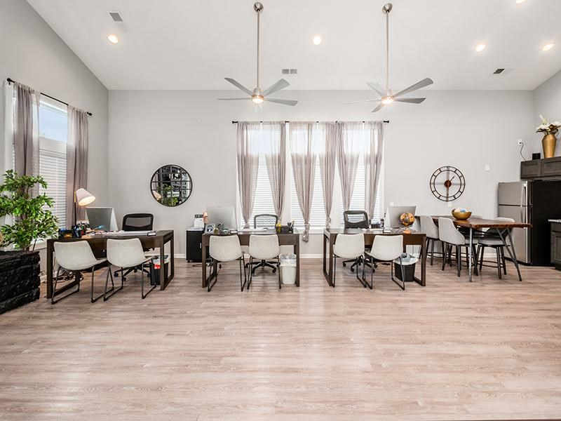 A well-lit room with a dining table and chairs, a desk with a computer, and a ceiling fan.