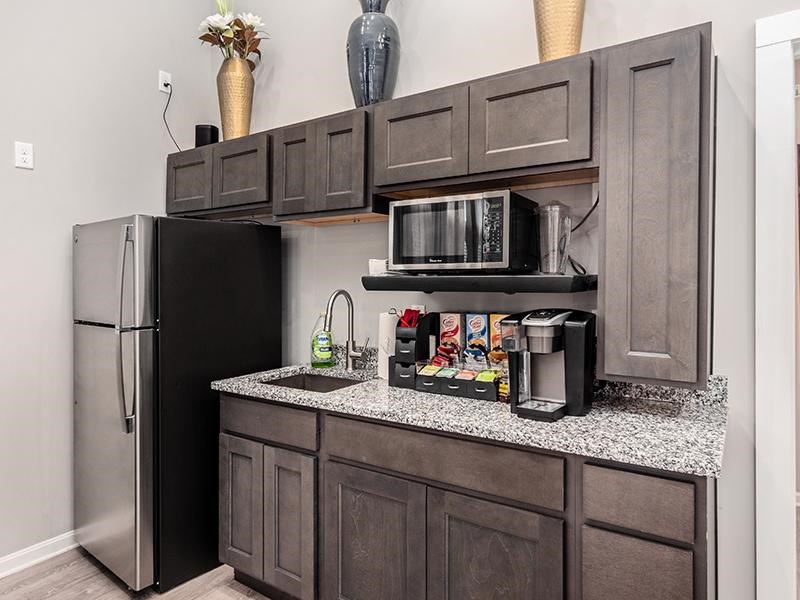A kitchen with a black refrigerator and a black microwave on a granite countertop.