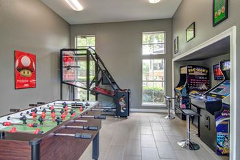 A room with a foosball table and arcade games.