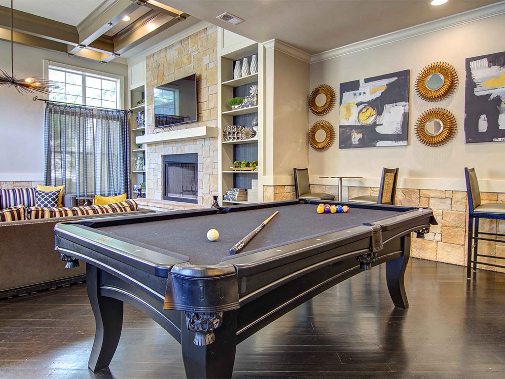 A pool table is in the middle of a room with a fireplace and a TV.