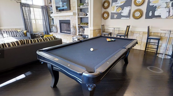 A pool table is in the middle of a room with a fireplace and a couch.
