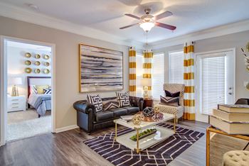 A living room with a black couch, a coffee table, and a painting on the wall.
