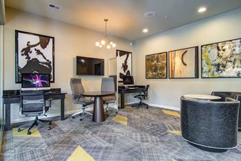 A conference room with a large table and chairs, a television, and framed artwork on the walls.