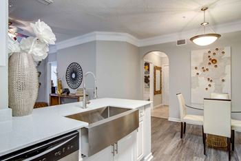 A modern kitchen with a white countertop and a stainless steel sink.