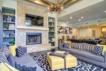 A living room with a grey couch and a yellow ottoman.