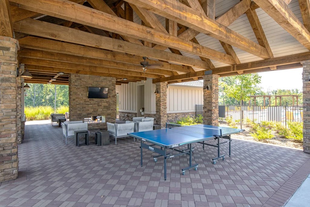 A patio with a table and chairs and a TV on the wall.