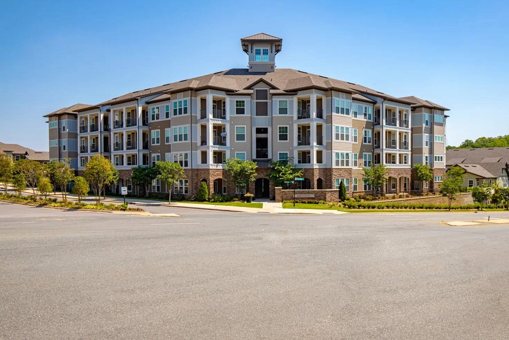 A large apartment building with a parking lot in front.