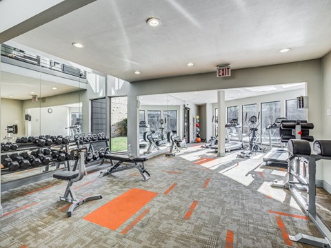 A gym with a variety of equipment including treadmills, weights, and exercise machines.