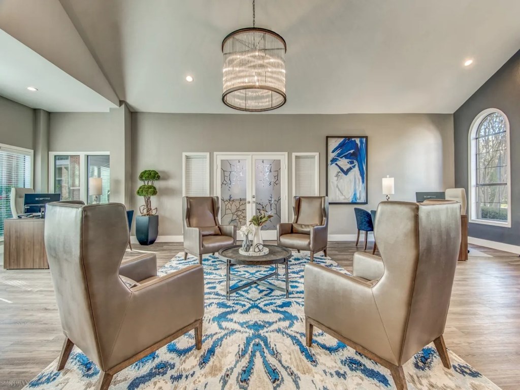 A living room with a large rug and a chandelier.