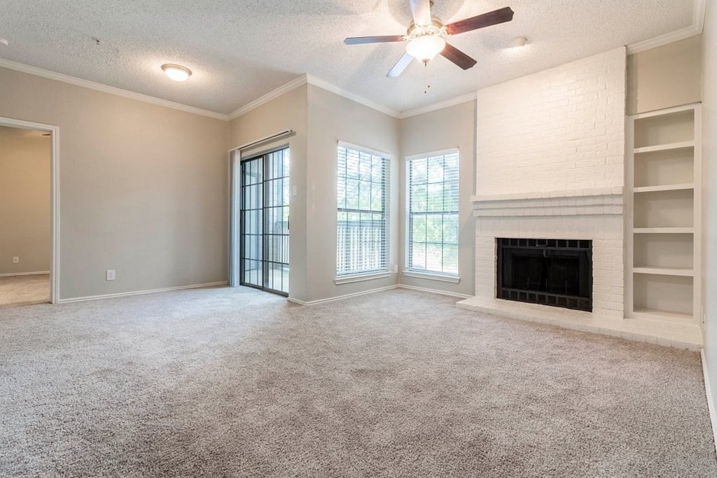 A spacious living room with a fireplace and a ceiling fan.