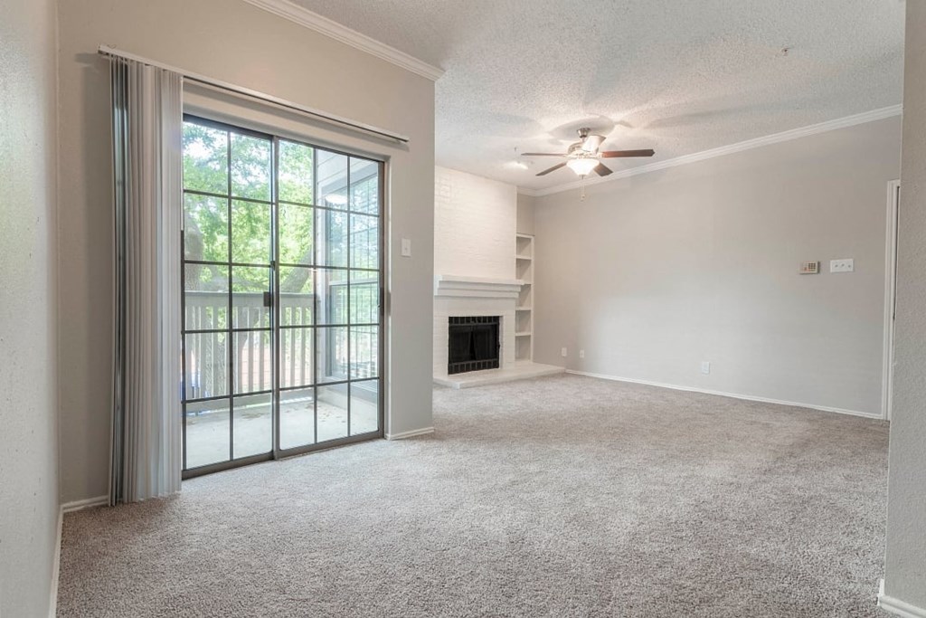 A room with a carpet floor, a fireplace, and a ceiling fan.