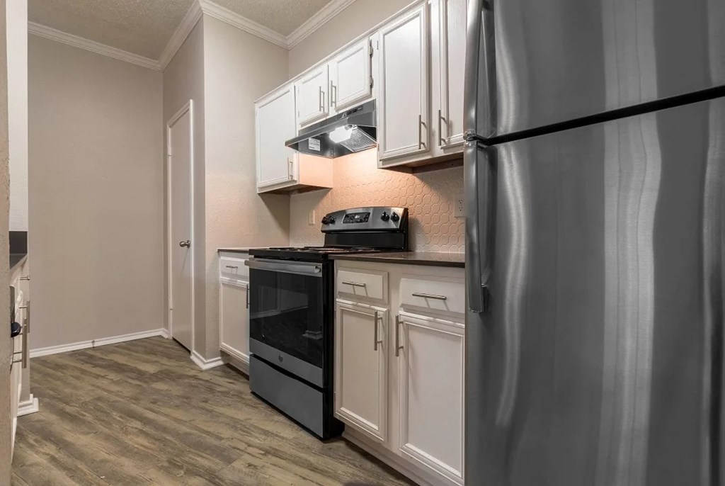 A kitchen with a black fridge and white cabinets.