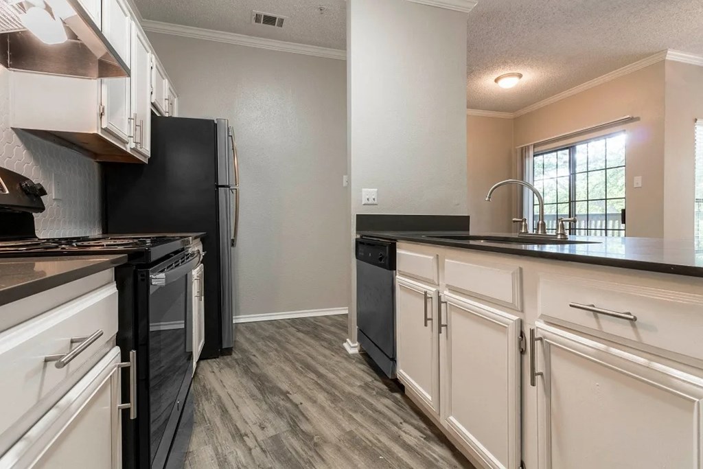 A kitchen with black appliances and white cabinets.
