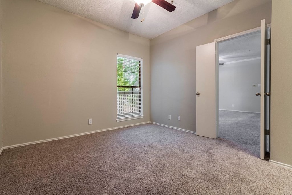A room with a carpeted floor and a window with blinds.