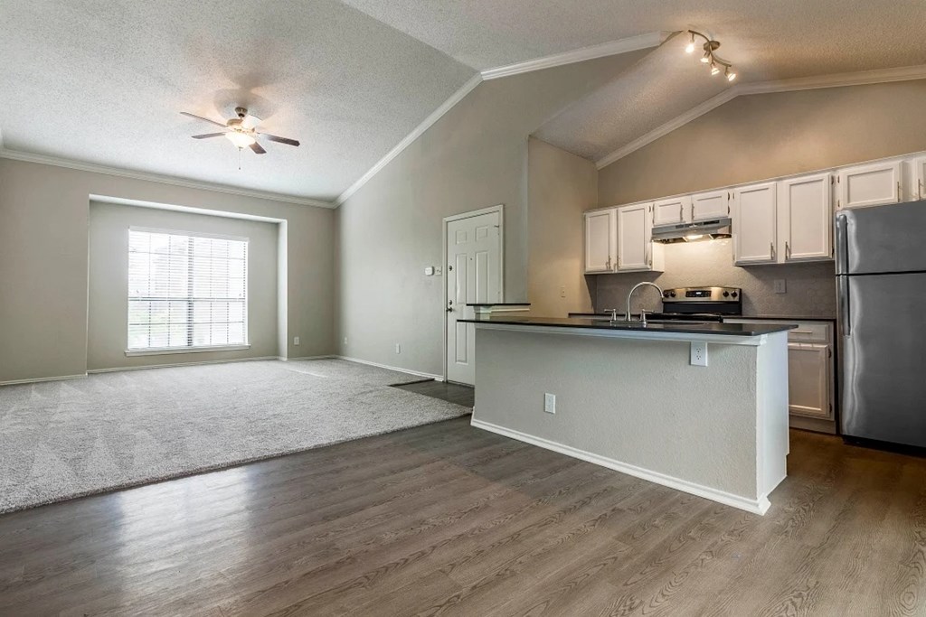 A kitchen with a refrigerator, stove, and cabinets.