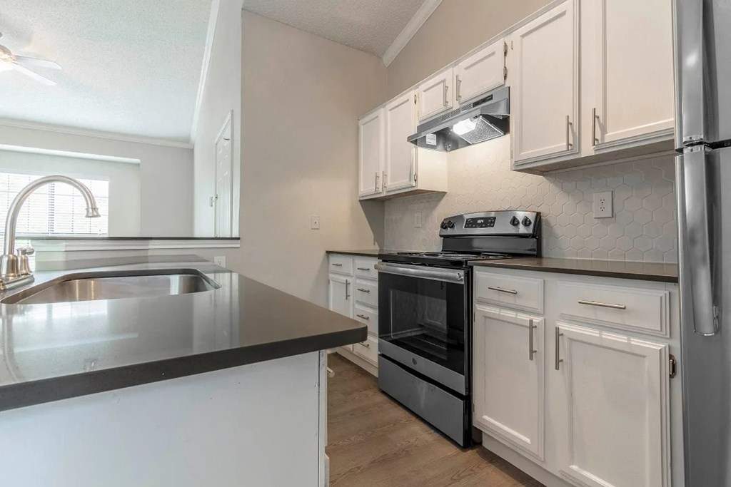 A modern kitchen with white cabinets and a black countertop.