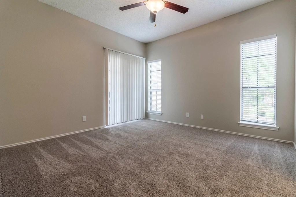 A room with a carpeted floor and a ceiling fan.