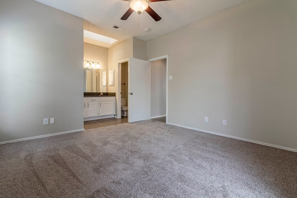 A room with a carpeted floor and a ceiling fan.