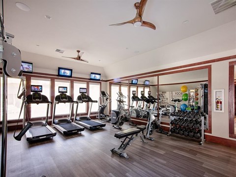 A gym with treadmills, exercise bikes, and a fan.