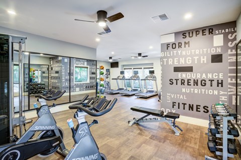 A gym with a row of stationary bikes and a wall of motivational words.