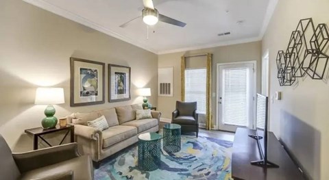 A living room with a couch, chair, and a table with a green vase on it.