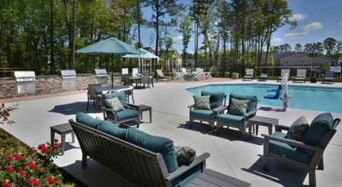 A pool area with a blue umbrella and chairs.
