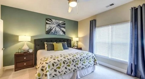 A bedroom with a large bed and a ceiling fan.