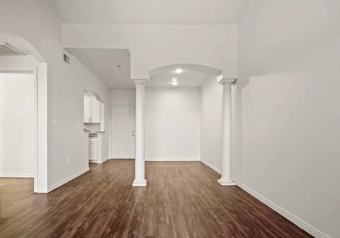 A room with white walls and wooden flooring with a white archway.