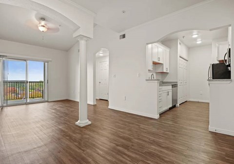 A spacious living room with a sliding glass door leading to a balcony.
