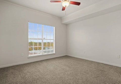 A room with a ceiling fan and a window with blinds.