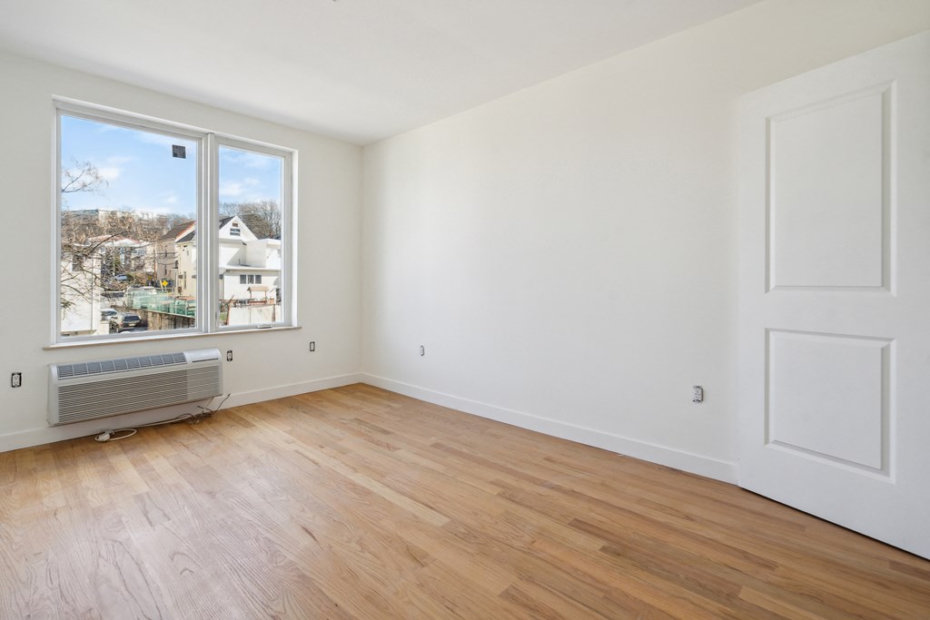 an empty living room with a large window and wooden floors