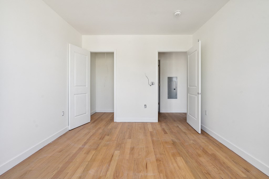 a living room with white walls and wooden floors and white doors