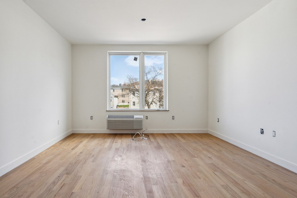 an empty room with wooden floors and a large window